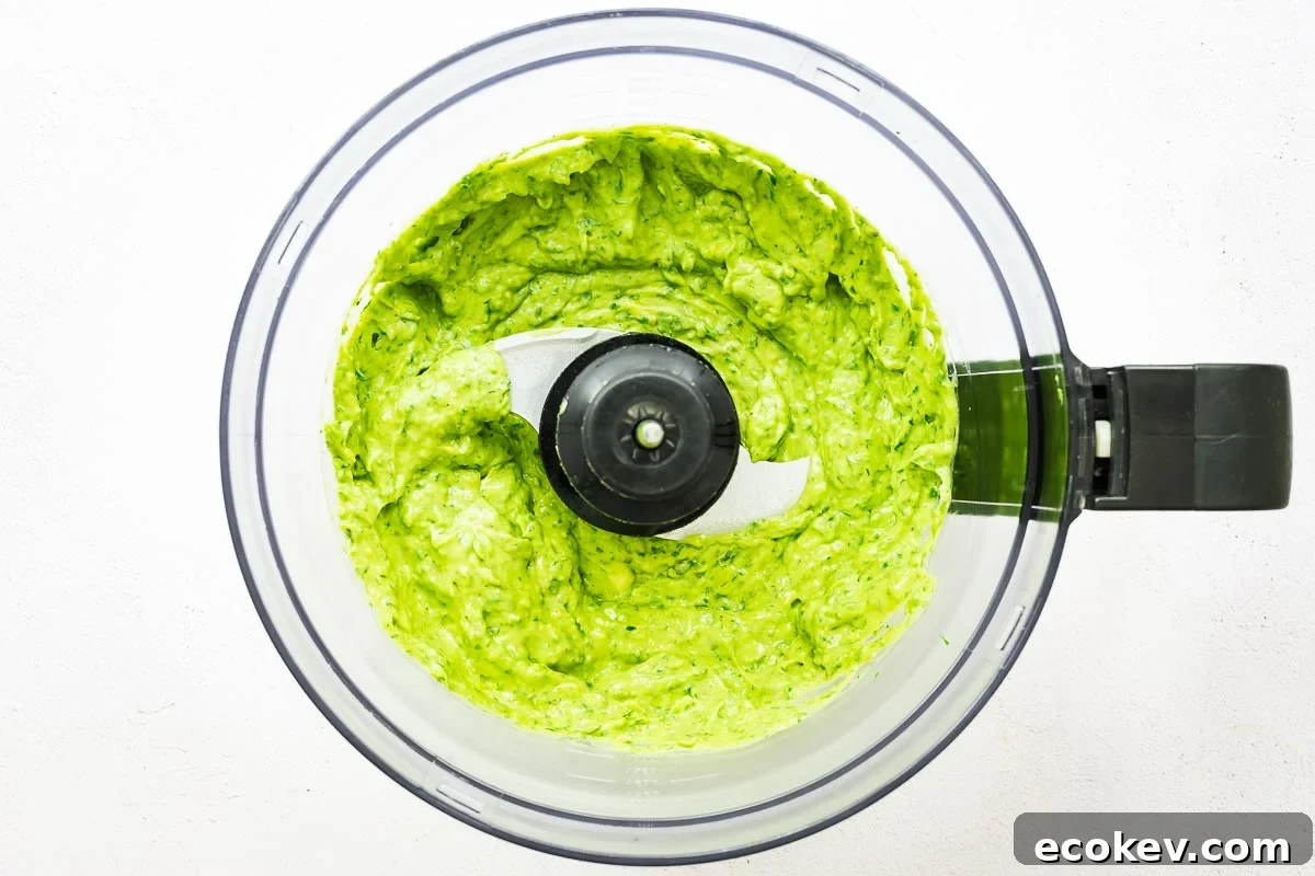 Smooth and creamy vegan green goddess sauce in a food processor bowl.
