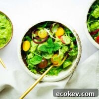 Vegan avocado green goddess dressing drizzled over a tomato and herb salad.