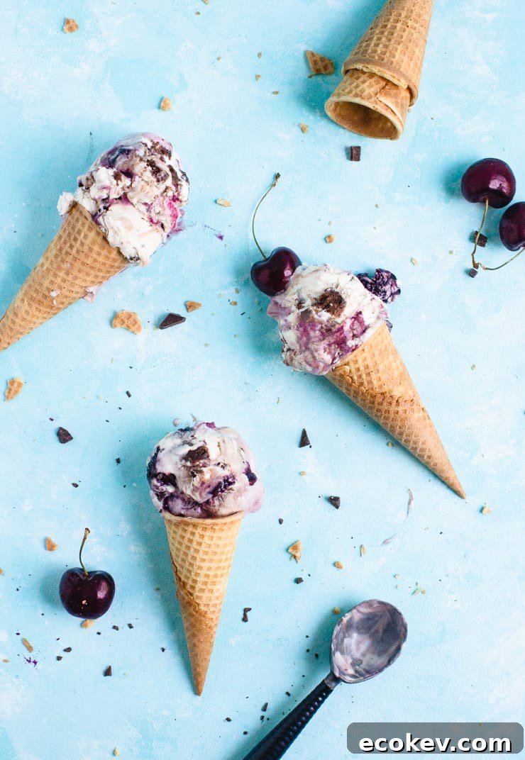Three ice cream cones with cherries and chunks of chocolate scattered about
