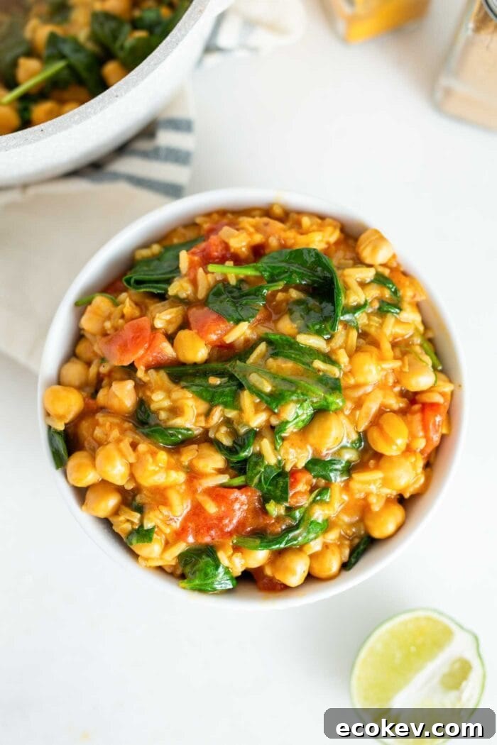 A bowl of chickpea stew with rice, spinach and tomato.