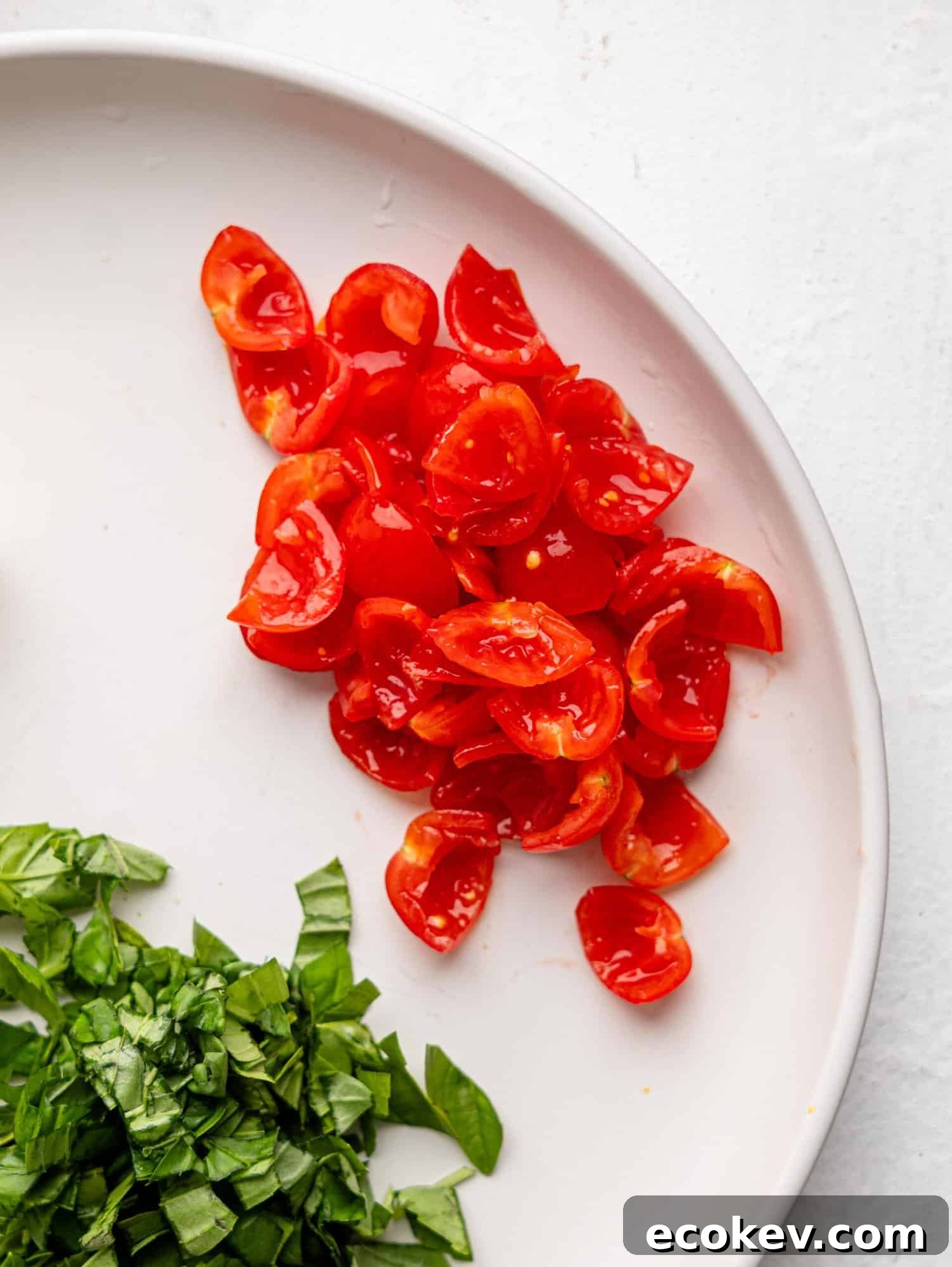 Cherry tomatoes cut into quarters with seeds removed on a white plate.