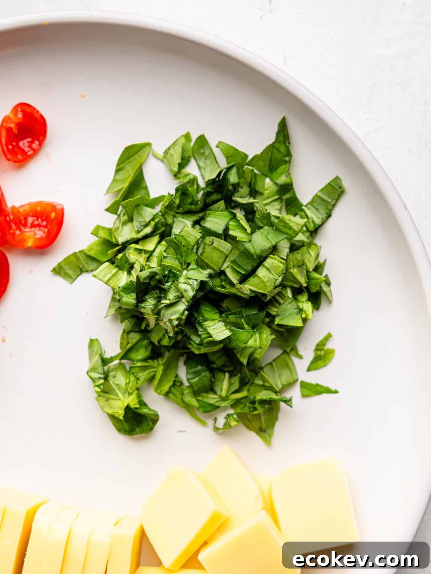 Roughly chopped basil on a white plate.