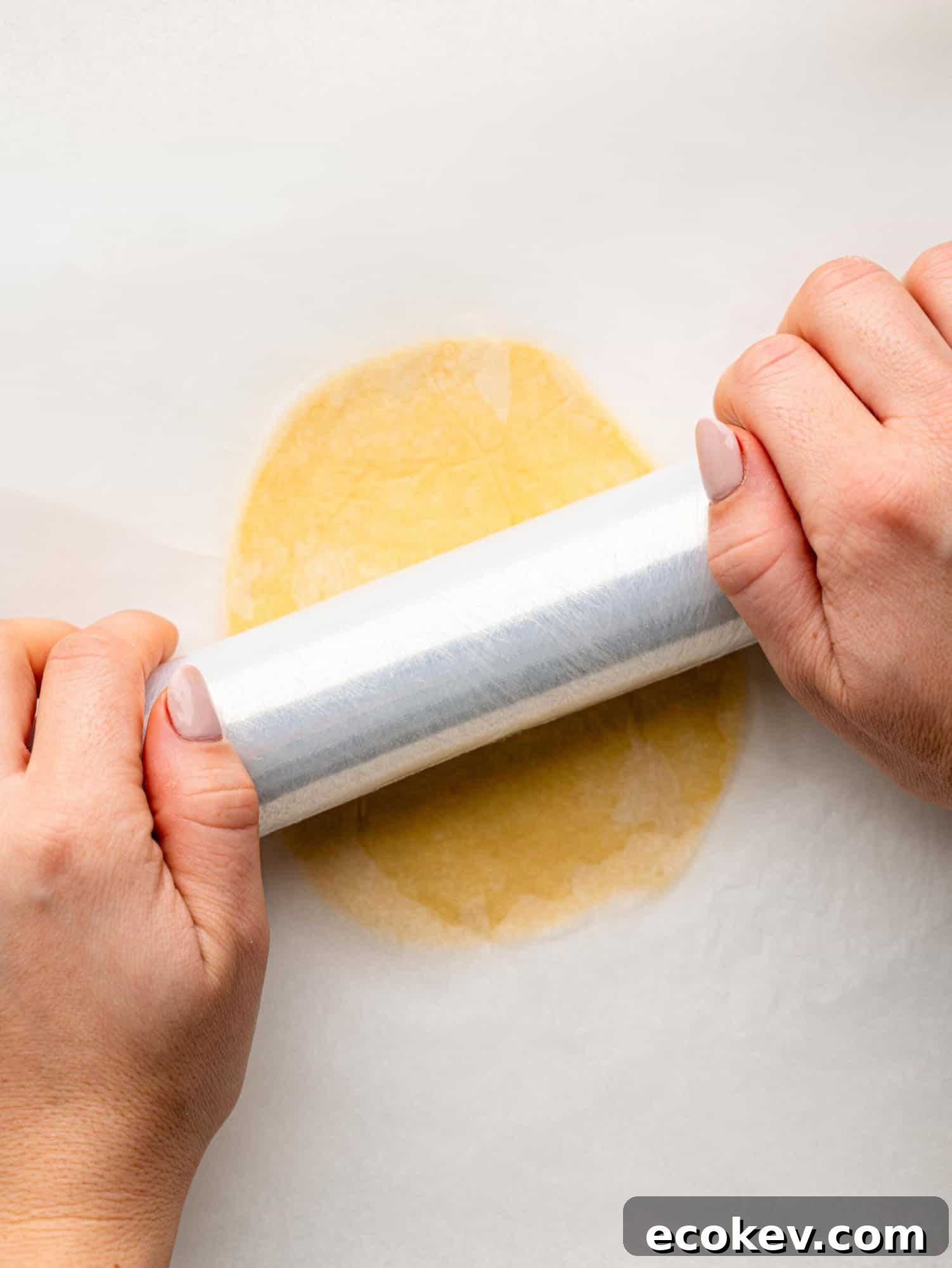 Rolling out an empanada disk with clingwrap.