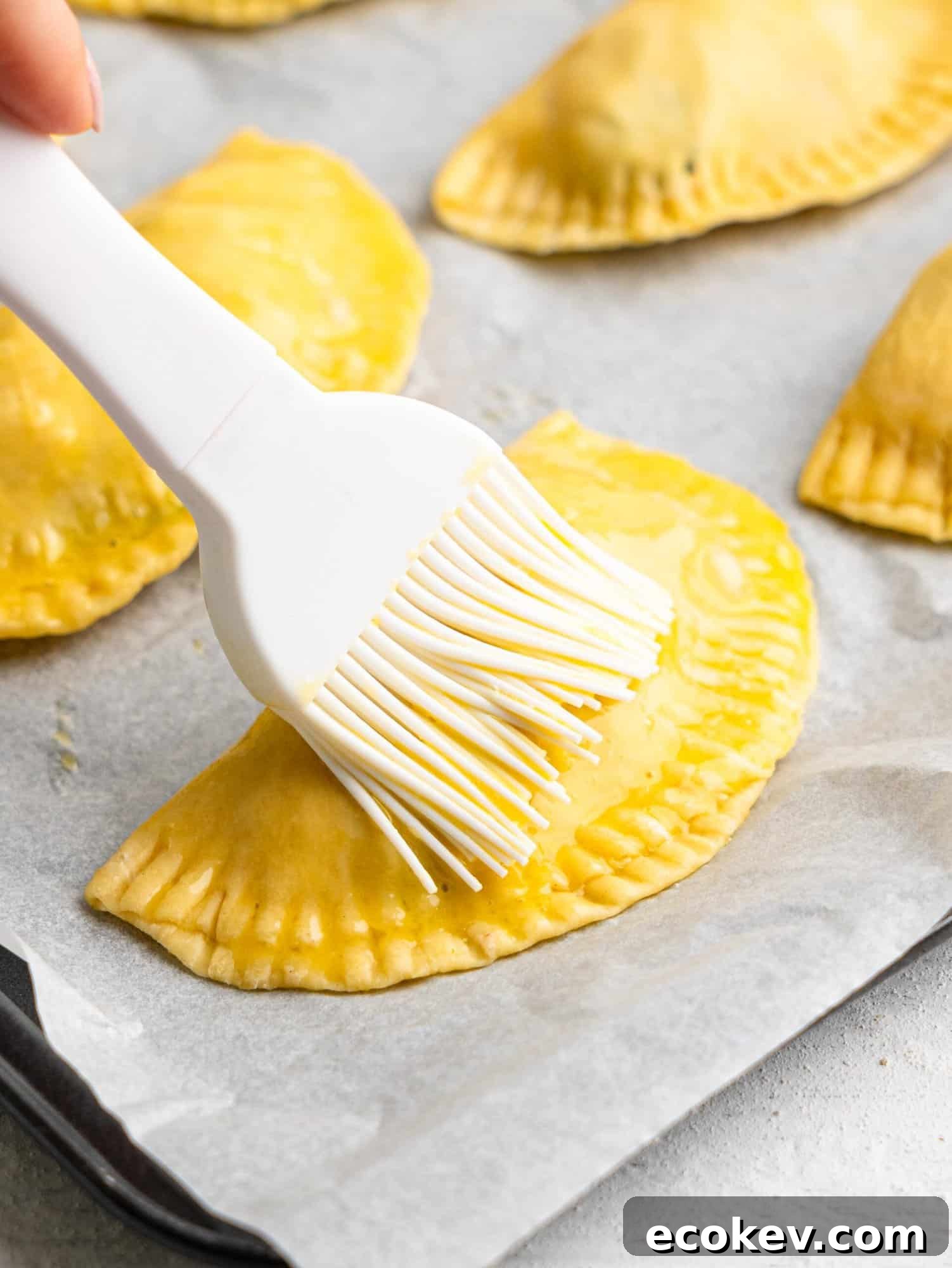 Brushing an empanada with an egg wash.