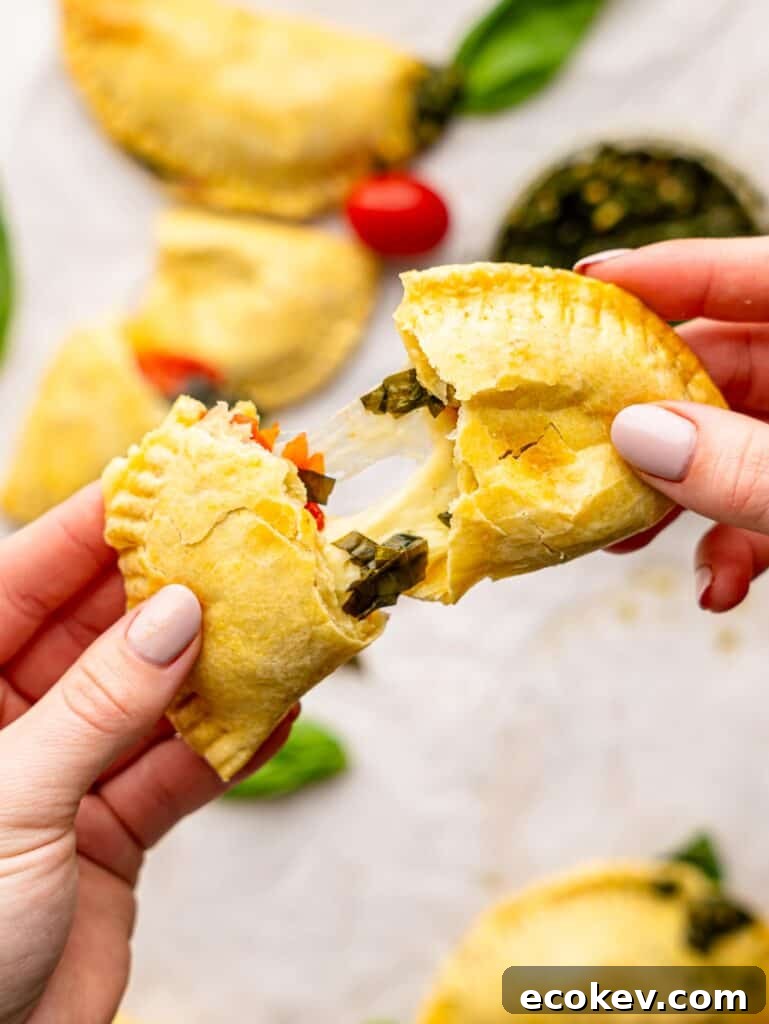 Someone tearing a caprese empanada in half.