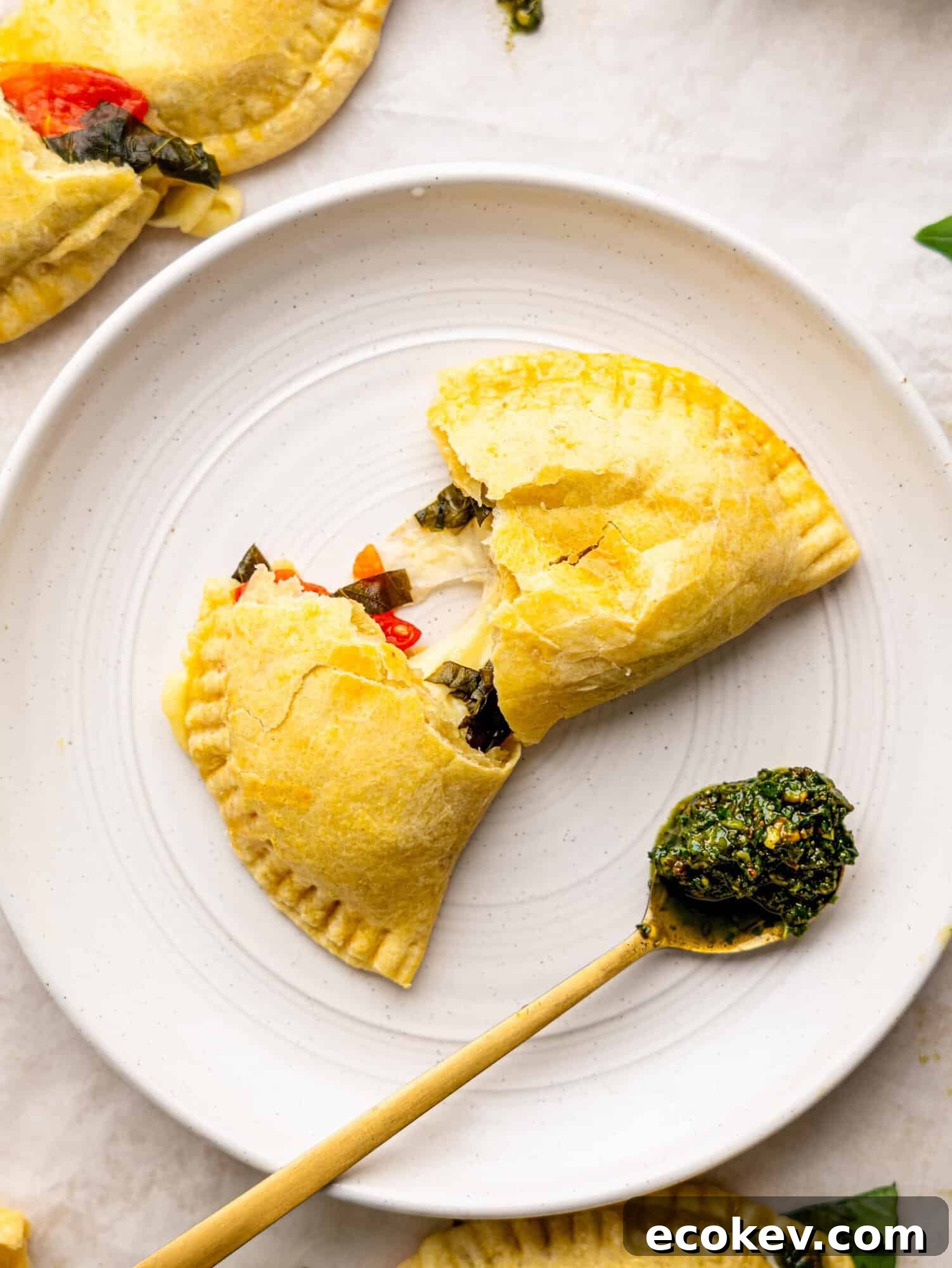 A caprese empanada torn in half on a white plate.