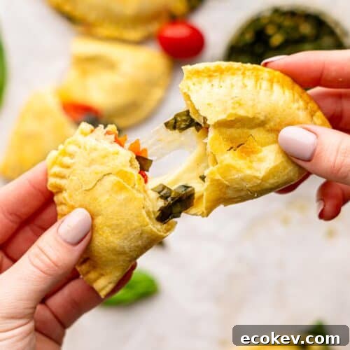 Someone tearing a caprese empanada in half.