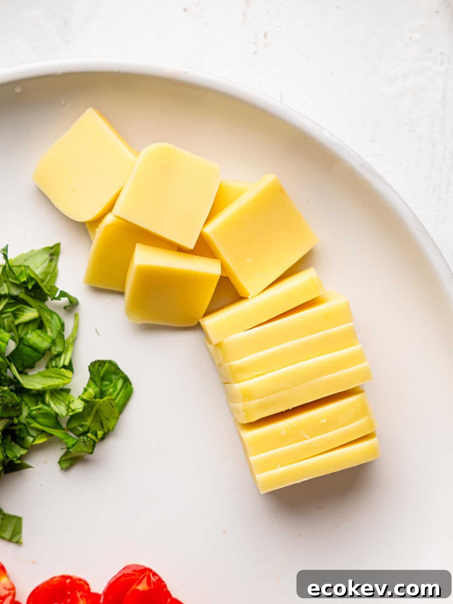 Mozzarella sliced into small pieces on a white plate.