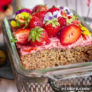 Strawberry banana cake decorated in a loaf pan with a slice removed.