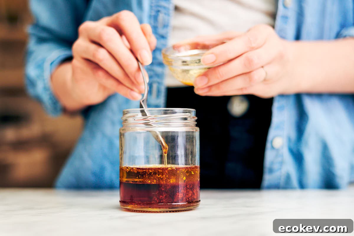 A woman adding ingredients to a glass jar to make sumac vinaigrette.