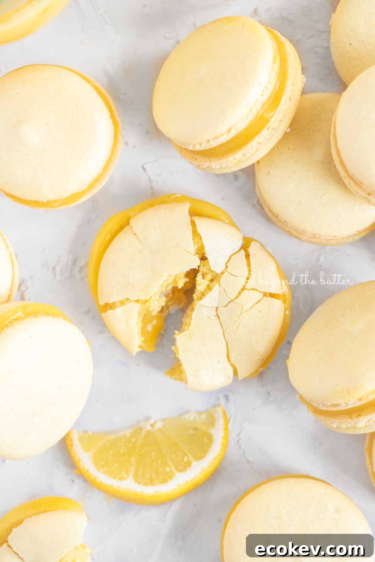 Overhead image randomly placed lemon macarons with the center macaron broken apart | All Images © Beyond the Butter™