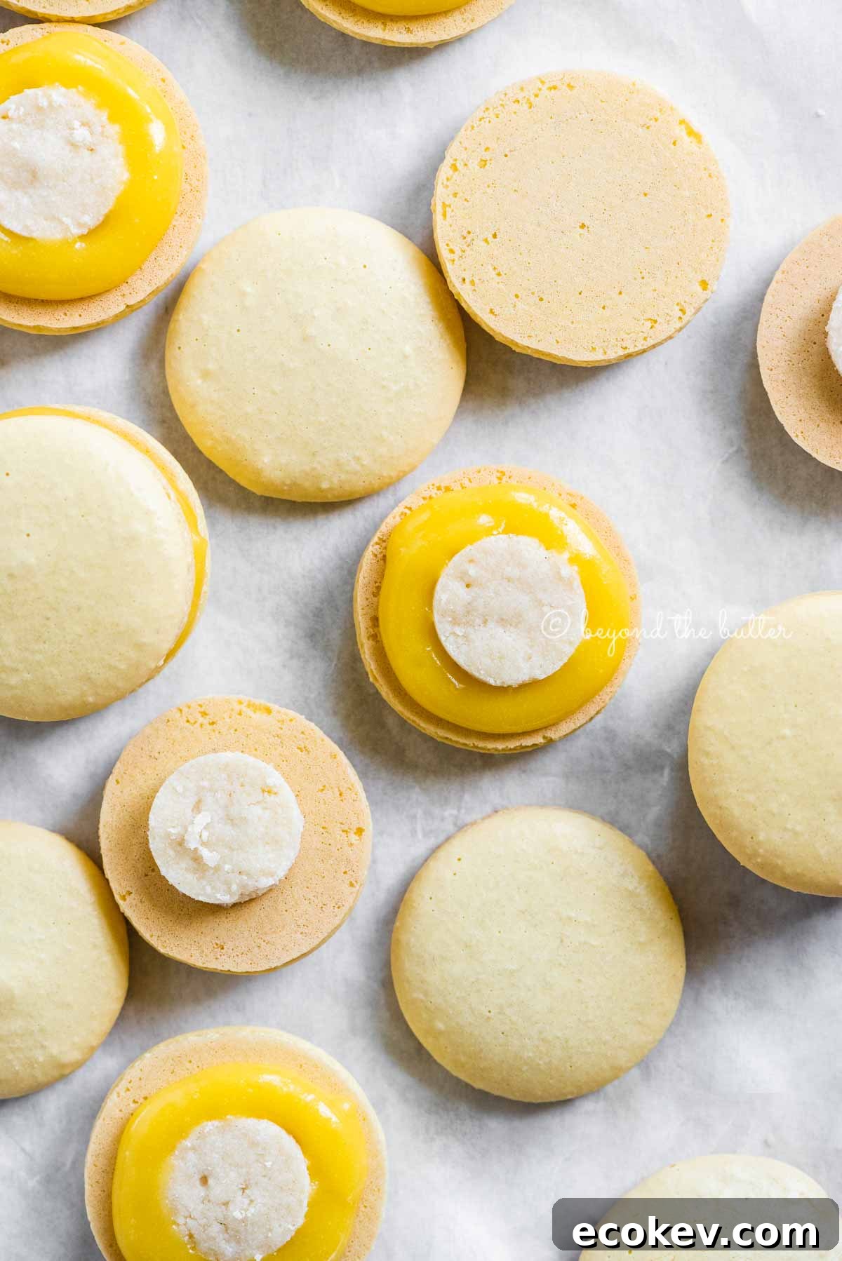 Overhead image of lemon bar macarons half opened topped with shortbread crust centers and lemon curd filling | All Images © Beyond the Butter™