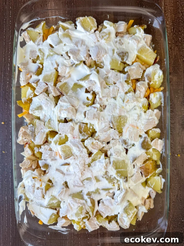 A thin layer of sour cream spread over a chicken potato casserole.