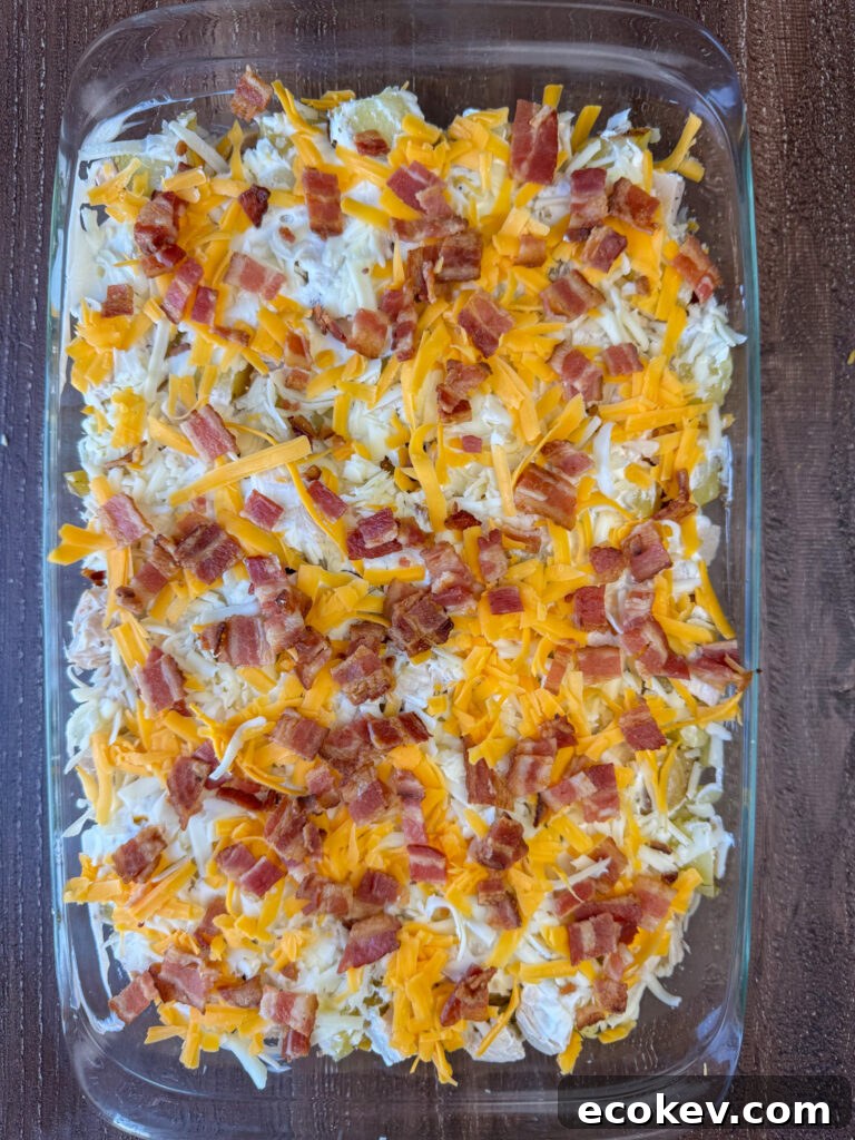 Hearty chopped bacon sprinkled over cheddar cheese and Monterey Jack cheese on top of a casserole.