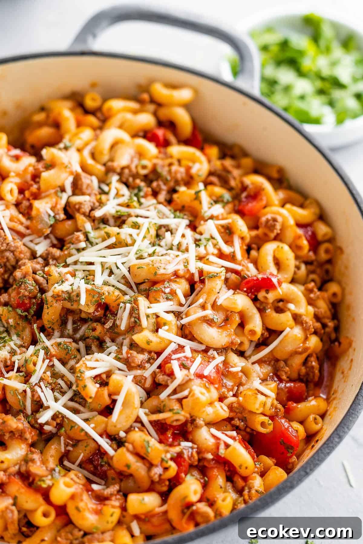 A Gray Pot Full of American Goulash Topped with Chopped Parsley and Grated Parmesan