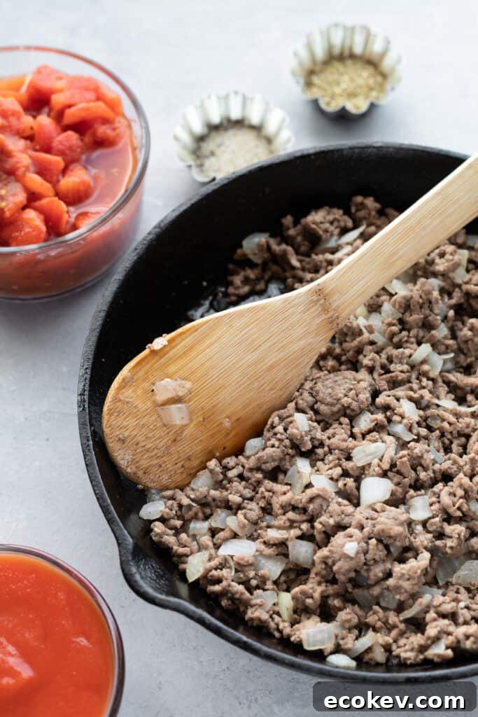 Browned Ground Beef and Chopped Onions Being Stirred by a Wooden Spoon