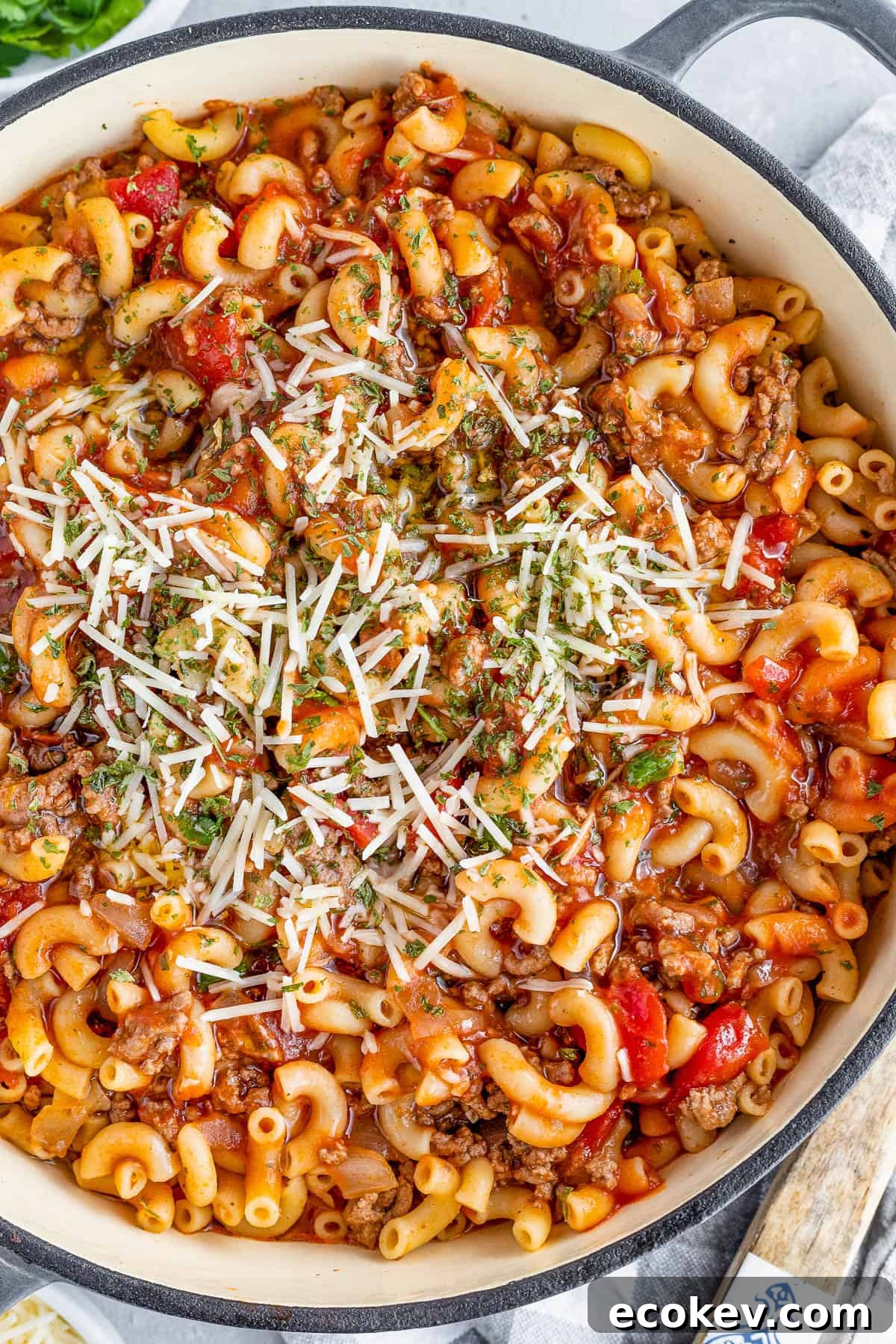 overhead shot of a Gray Pot Full of American Goulash Topped with Chopped Parsley and Grated Parmesan