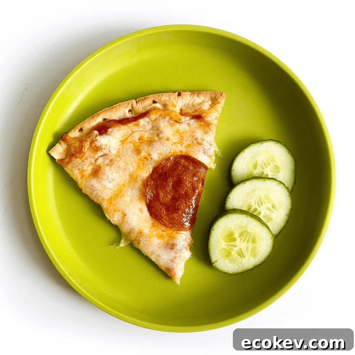 green plate with pizza slice and three cucumbers