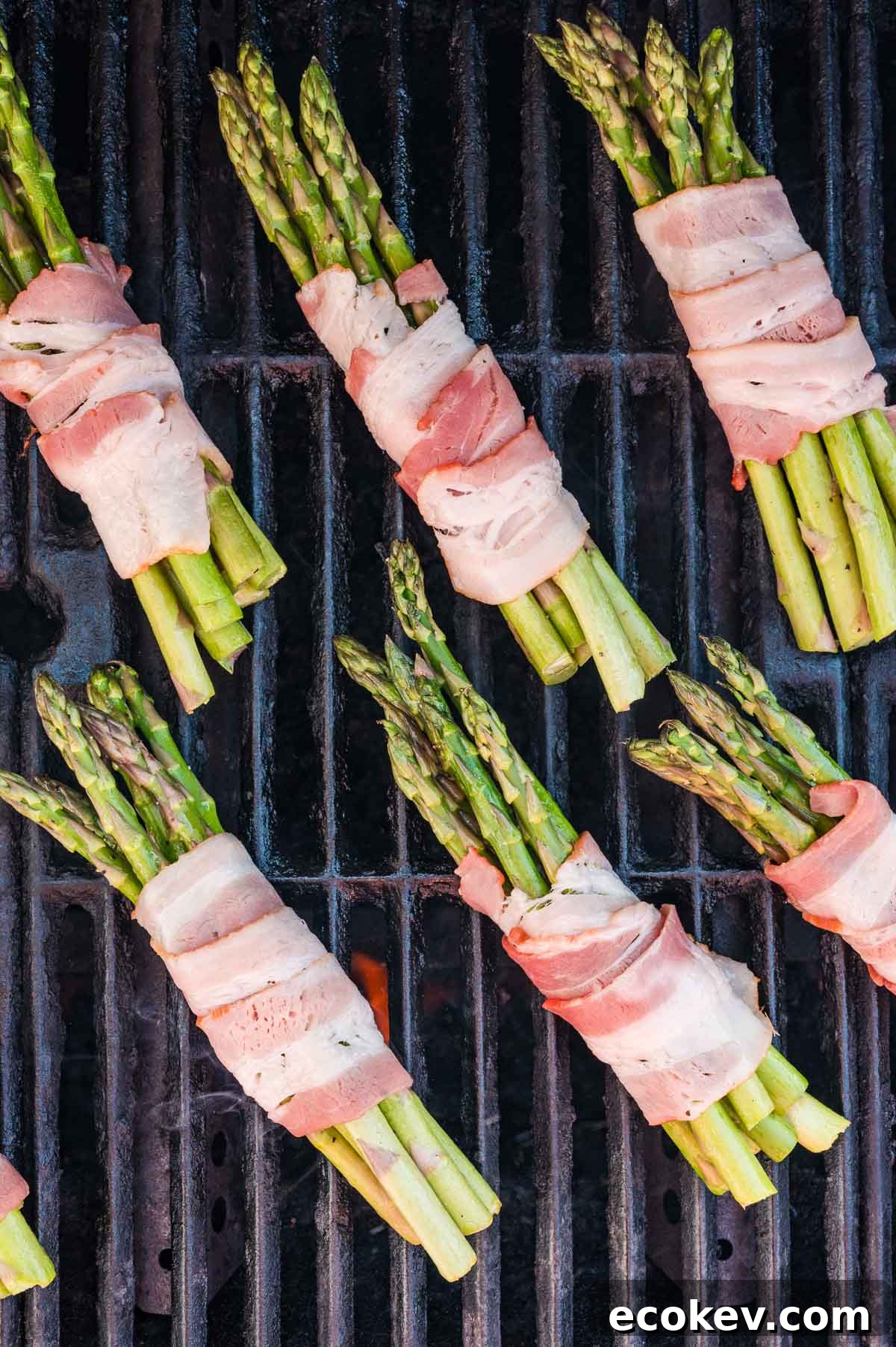 Bundles of asparagus wrapped in bacon grilling on a barbecue.