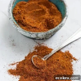 Homemade Fajita Seasoning in a turquoise stoneware bowl next to a pile of seasoning with a silver teaspoon