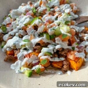 A bowl of seasoned ground beef with roasted sweet potatoes and toppings.