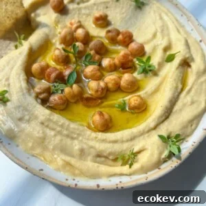 A bowl of creamy hummus topped with whole chickpeas and olive oil.