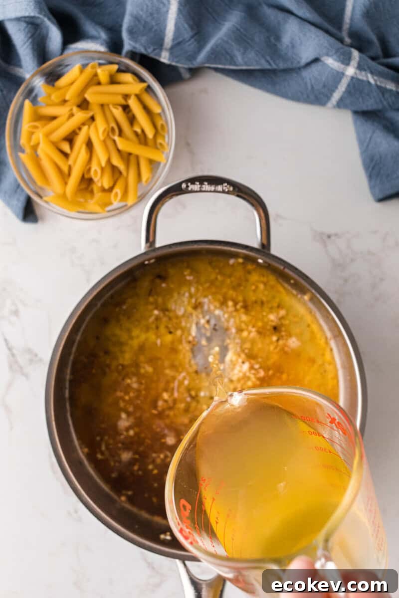 pouring the broth into the skillet with the cooked garlic.