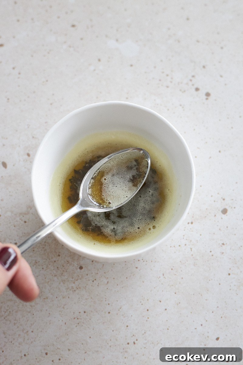 Browned butter mixture with sage in a small white bowl.