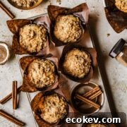 Streusel topped muffins in brown paper parchment liners in a muffin tin.