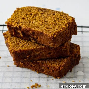 Three slices of gluten free pumpkin loaf stacked on a plate.