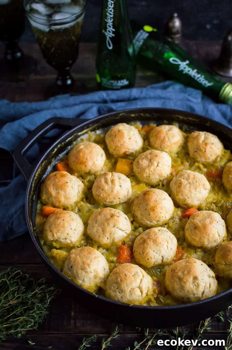 Vegan vegetable and pearl barley stew topped with herby dumplings in a cast iron pan with Appletiser in the background.
