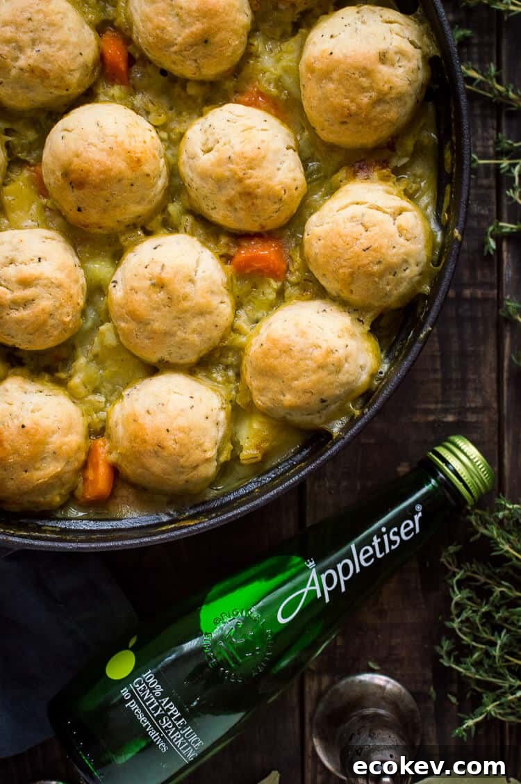 Close up of a pan of vegetable and pearl barley stew with herby dumplings and a bottle of Appletiser