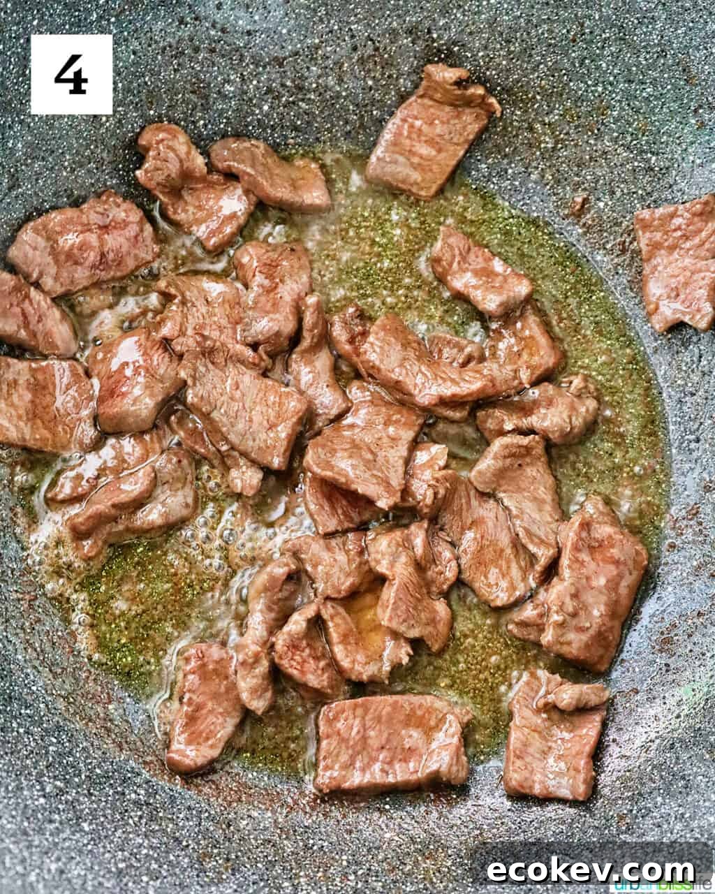 sliced steak cooking in a large wok.