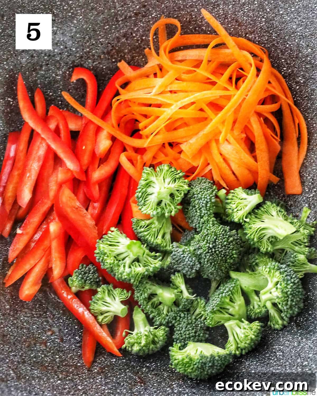 red bell peppers, carrots, and broccoli in a large wok.