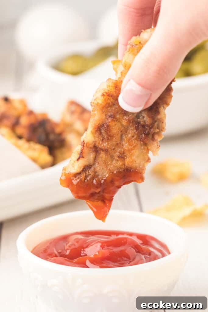 hand dipping a steak finger into ketchup