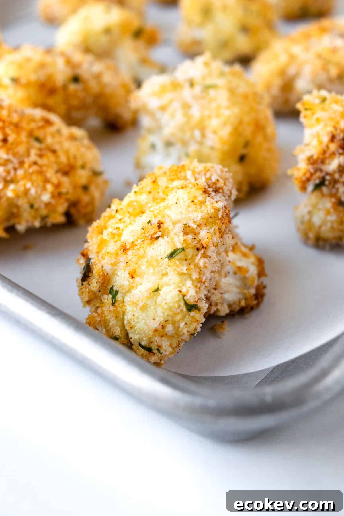 Baked Crispy Cauliflower Bites closeup of one on a baking sheet.