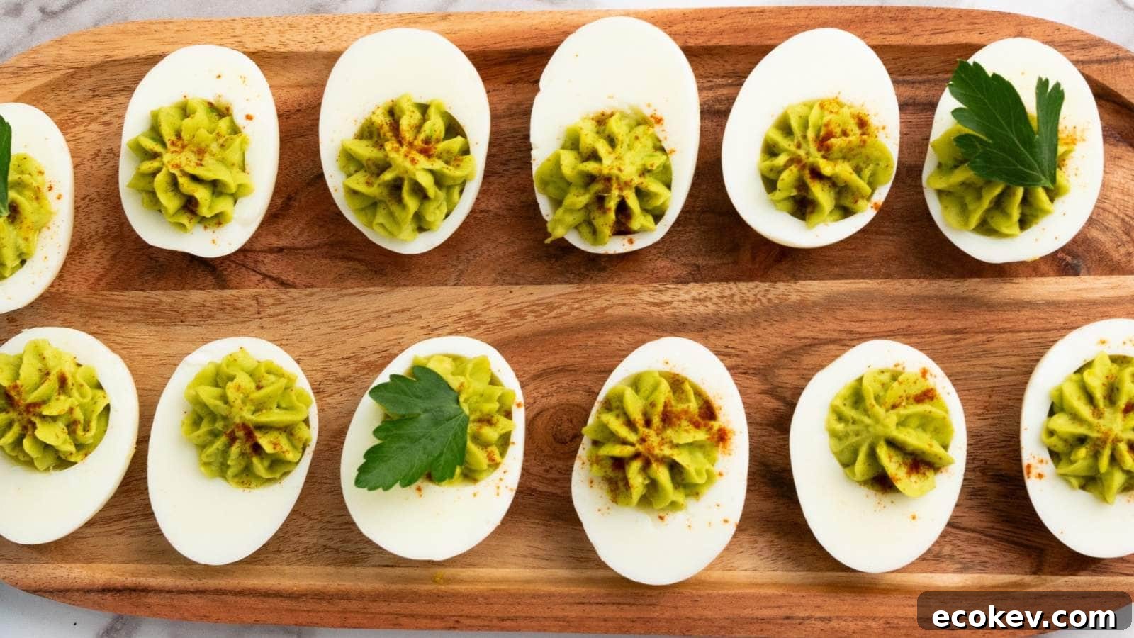 Deviled eggs topped with green filling and paprika are arranged on a wooden serving tray, garnished with parsley leaves.