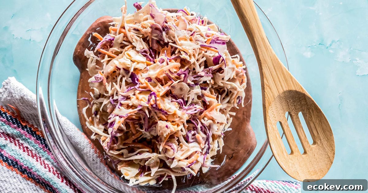 A picture of keto coleslaw in glass bowl with wooden spoon.