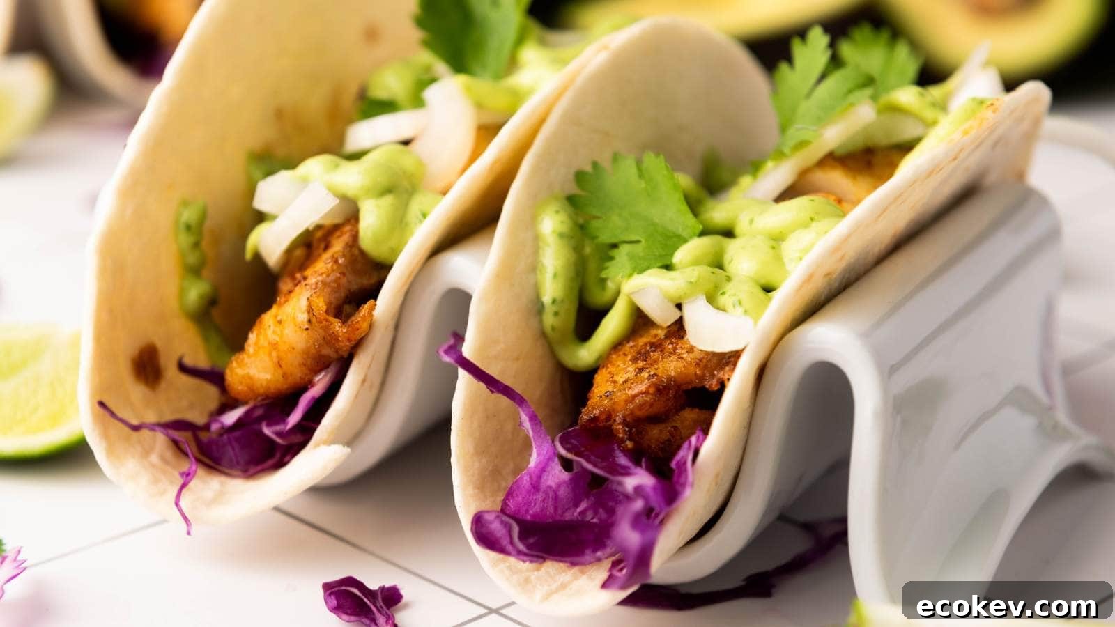 Two fish tacos filled with cooked fish, shredded purple cabbage, chopped onions, cilantro, and drizzled with a green sauce.