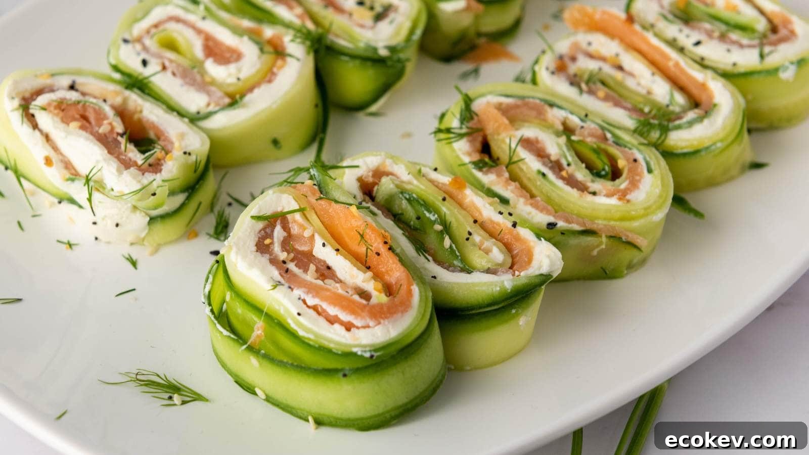Cucumber roll ups on a plate filled with cream cheese, smoked salmon, and garnished with dill.
