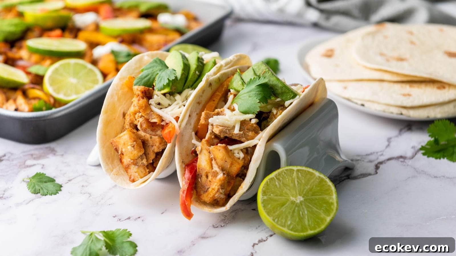 Two chicken fajitas with shredded cheese, avocado slices, and cilantro in taco holders.