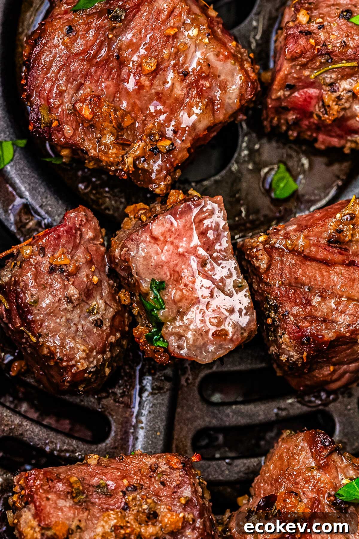 A close up picture of the finished garlic steak bites in an air fryer basket. 