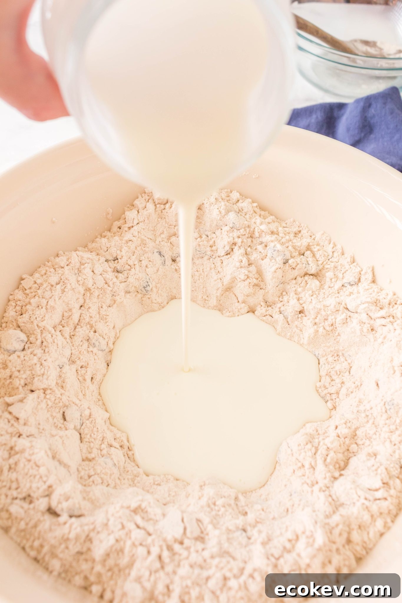 Buttermilk being poured into a well of flour.