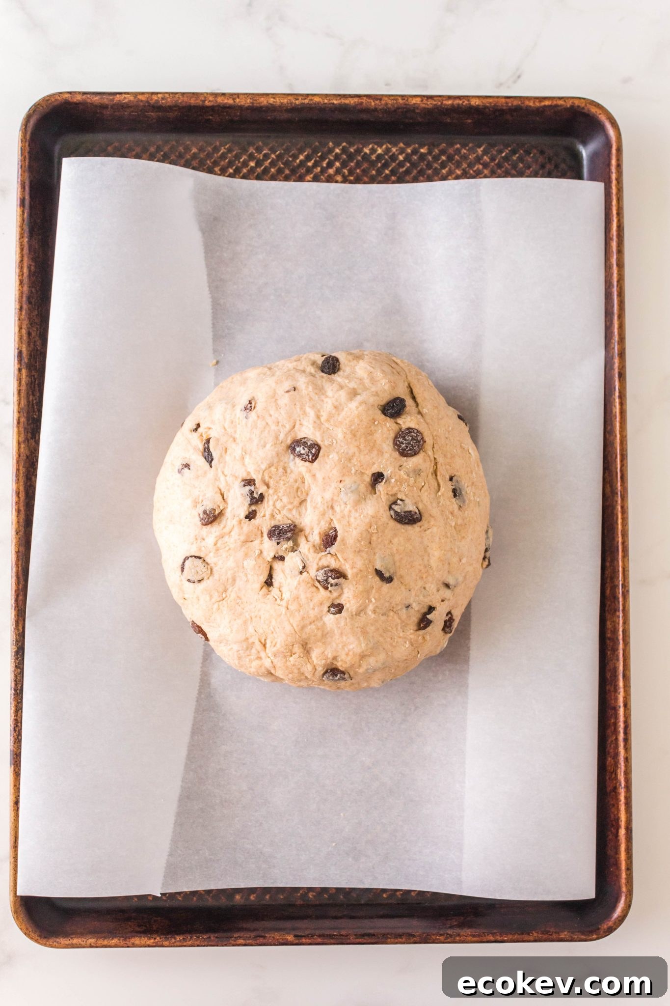 Top down view of a round shaped loaf of soda bread on a baking sheet.