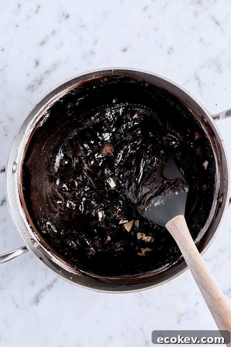 Mixed triple chocolate brownie batter in saucepan with spatula