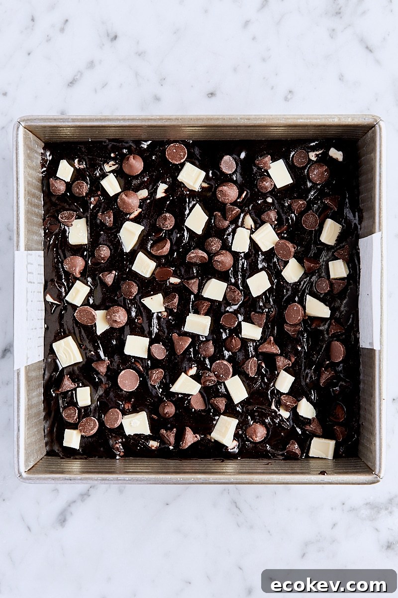 Triple chocolate brownie batter spread into parchment-lined square baking pan
