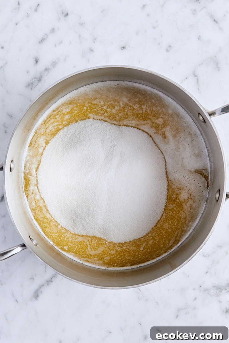 Granulated sugar added to saucepan with melted butter