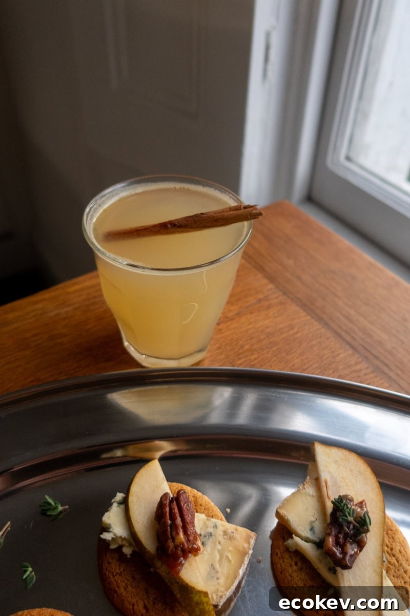 A warm apple toddy, garnished with a cinnamon stick next to a tray of canapes - Georgie Mullen