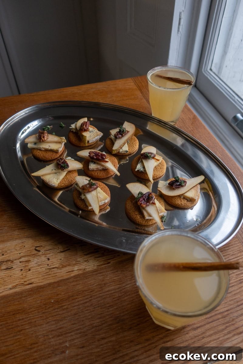 Two glasses of hot apple toddy sat next to a silver tray of biscuit canapes - Georgie Mullen
