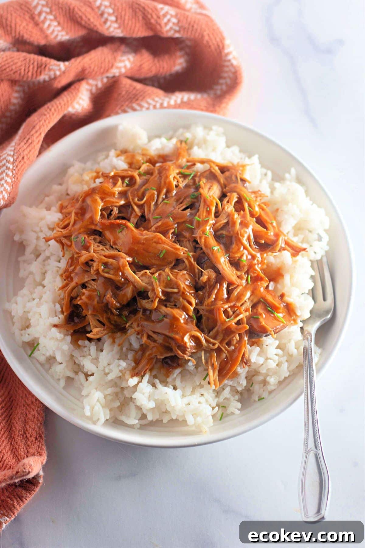 Shredded honey garlic chicken on top of a bed of rice.